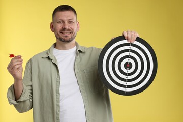 Targeting. Man with dart board and arrow on yellow background