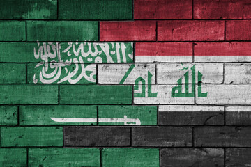 Fototapeta premium colourful painted big national flag of saudi arabia and flag of iraq on a massive old brick wall background. concept