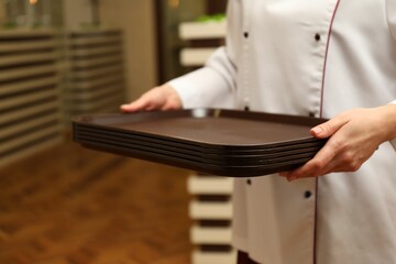 School canteen worker holding plastic trays for food indoors, closeup