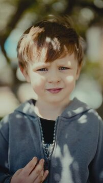 Little kid boy looking seriously at the camera in vertical footage. Thoughtful expression, child portrait, ideal for family, emotions, parenting, or social themes
