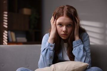 Sad teenage girl on sofa at home