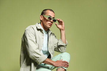 Fashionable portrait of handsome man in stylish outfit on green background, space for text