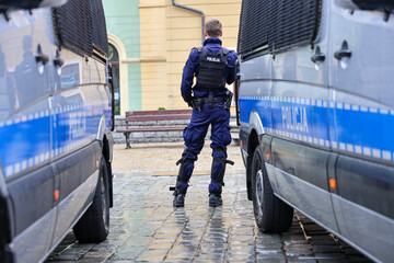 Policjanci prewencji przy radiowozie w mundurach na służbie.