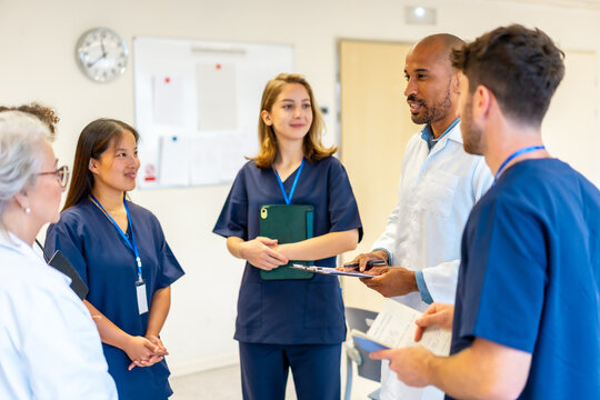 Medical team meeting discussing patient charts in hospital room