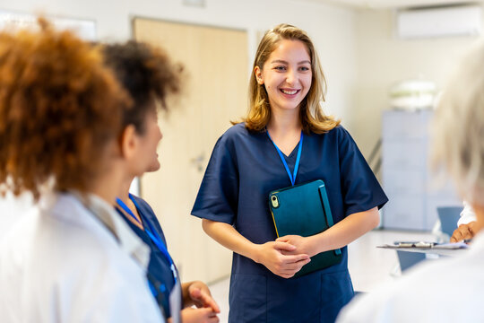 Young nurse smiling during hospital meeting with medical team - Powered by Adobe