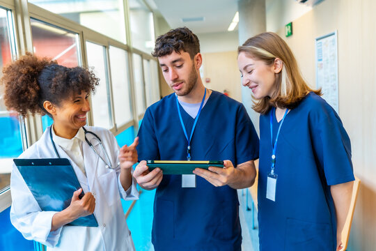 Medical team discussing patient data using digital tablet in hospital corridor - Powered by Adobe