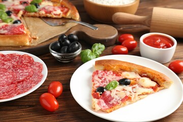 Tasty pizza and ingredients on wooden table, closeup