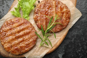 Delicious hamburger patties and spices on black table, top view