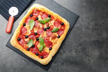 Tasty homemade pizza and cutter on grey table, top view. Space for text