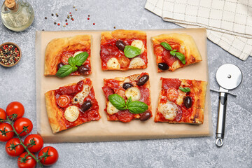 Tasty homemade pizza, ingredients and cutter on grey table, flat lay