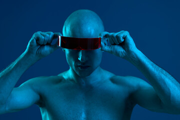 Futuristic man with red visor poses against a blue background, embracing a cyberpunk aesthetic....