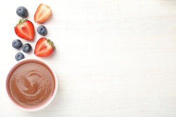 Baby food. Tasty puree in bowl and different ingredients on white wooden table, flat lay. Space for...