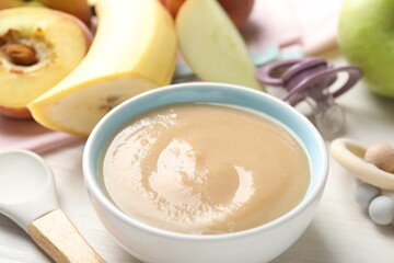 Baby food. Tasty puree in bowl, different ingredients, teether and pacifier on table, closeup