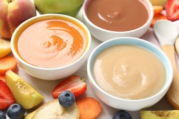 Baby food. Tasty puree in bowls and different ingredients on table, above view