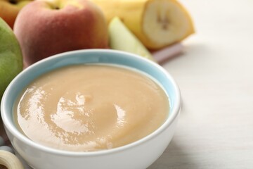 Baby food. Tasty puree in bowl and different ingredients on white table, closeup