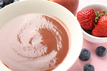 Baby food. Tasty puree in bowl and ingredients on pink background, closeup