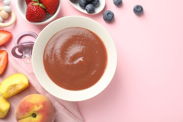 Baby food. Tasty puree in bowl, pacifier, teether and ingredients on pink background, flat lay....