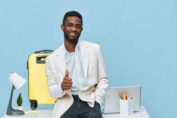 Confident smiling man with African descent in stylish white blazer and light blue shirt standing at...