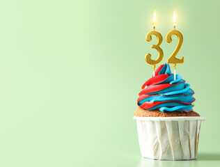 Yummy cupcake with burning number shaped candles on light turquoise background, space for text....