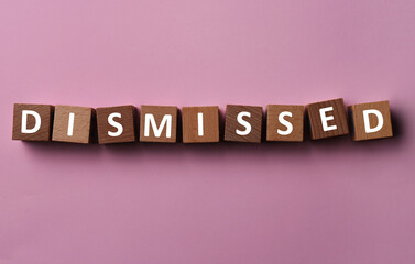 Word Dismissed made of wooden cubes on pink background, top view
