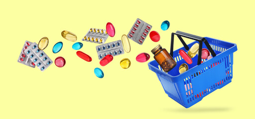Shopping basket and different medications in air on pale yellow background, banner design