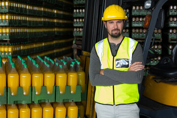 Male worker leaning against forklift wearing reflective vest in depot with juice crates, copy space © wavebreak3