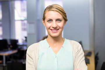 Female office professional standing and smiling at modern office with desks monitors and keyboard
