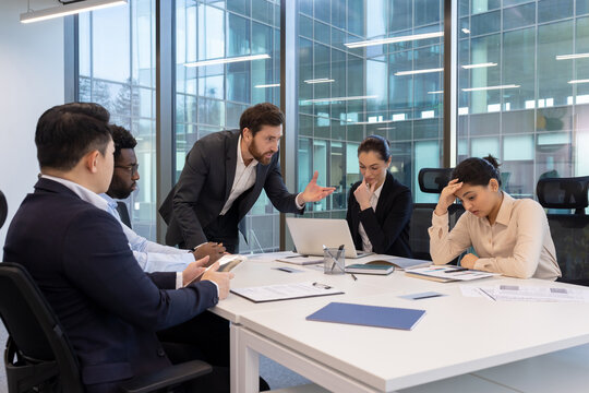 A business team is having a tense meeting in an office setting, with a displeased manager and concerned colleagues. - Powered by Adobe