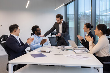 A diverse team celebrates success in a modern office, with applause and a leader's acknowledgment.