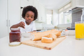 African American boy sitting at modern kitchen island eating cereal with spoon and orange juice © WavebreakMediaMicro