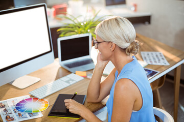 Dual-screen workstation showcasing monitor and laptop beside tablet with stylus on desk in studio