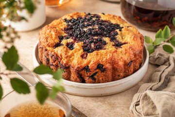 Blueberry cake on a plate on beige background with tea