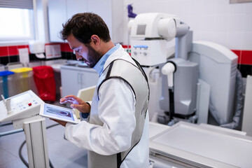 X-ray machine standing ready in hospital radiology room, with digital console and disposal bins