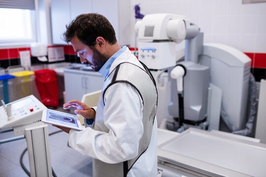 X-ray machine standing ready in hospital radiology room, with digital console and disposal bins
