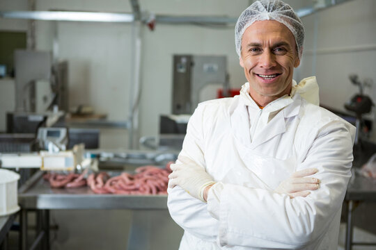 Senior man operating stuffing machine with raw sausages at meat facility in gloves, copy space