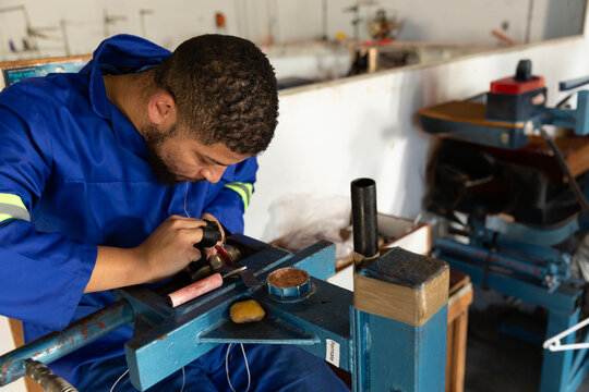 Metal component is grinding on polishing wheel at machine shop bench with sharpening stone
