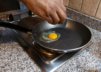 an egg just placed in a frying pan to fry,
