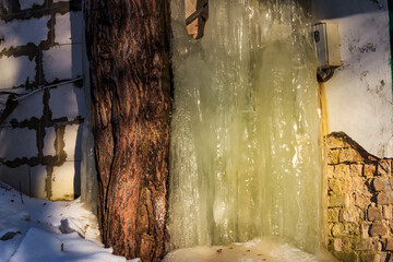 Thick layer of ice built up on the wall of a garage during the winter season