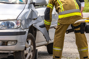 Naklejka premium Firefighters pull a man trapped in a car after a car accident