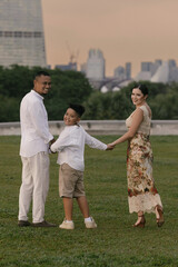 Obraz premium Elegant international family in Singapore. Asian father, Eastern European mother, and their child smiling near Marina Bay Sands. Diverse background and warm, joyful family moment outdoors