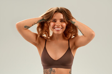 Smiling young woman with tattoos holding hair up, beauty, confidence and wellness concept