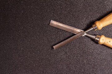 Close-Up of Two Metal Chisels on a Textured Dark Background