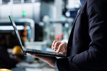 Industrial business analyst in suit inspecting renewable energy equipment, demonstrating attention to quality control and manufacturing efficiency. Ensures solar power advancement.