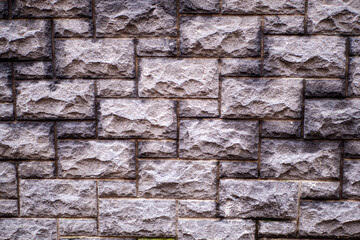 The wall is made of gray bricks and has a rough texture. The bricks are stacked in a way that creates a pattern, giving the wall a unique and interesting appearance