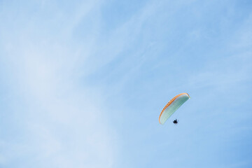 Paraglider flying high in the clear blue sky, extreme aerial sport symbolizing freedom, adventure, and outdoor recreation in natural open space