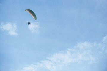 Paraglider flying high in the clear blue sky, extreme aerial sport symbolizing freedom, adventure, and outdoor recreation in natural open space