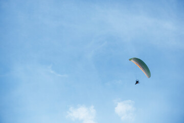 Paraglider flying high in the clear blue sky, extreme aerial sport symbolizing freedom, adventure, and outdoor recreation in natural open space