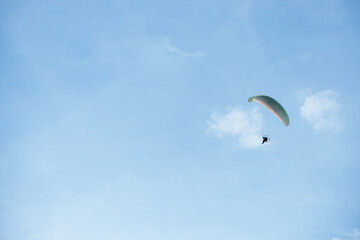 Paraglider flying high in the clear blue sky, extreme aerial sport symbolizing freedom, adventure, and outdoor recreation in natural open space