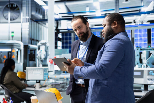 Multiethnic specialists engineers doing teamwork on modern production line for solar panels power, combining technical insight and collaboration for renewable energy infrastructure. - Powered by Adobe