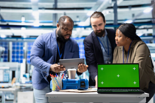 Team members in suits overseeing factory activity next to green screen, blending professionalism and technical expertise in the world of sustainable industrial energy. Cheaper power.